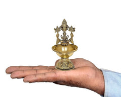Brass Lakshmi oil lamp diya on pedestal, held in hand, ornate engraved design