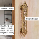 Golden brass door pull handle with ornate filigree flower panel and round backplate
