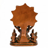 Brass Dakshinamurti Shiva statue back view, orange panel with green base and small idols