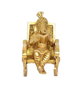 Golden brass Ganesha seated on ornate chair, hands holding book, front view