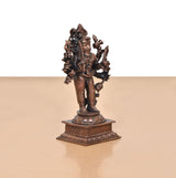 Copper Lord Kal Bhairav idol shown from an angle, holding weapons, on engraved base