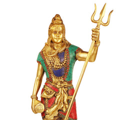 Brass Bholenath idol close-up, trident and jeweled face, green top with blue center