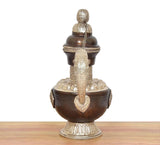 Traditional brass teapot showpiece, front view: dark brown body, chain, and engraved base