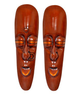 Pair of copper-brown tribal face plaques, symmetrical eyes and smiling mouths