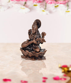 Small Copper Maa Saraswati idol seated on lotus, veena across lap, raised blessing hand