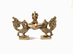 Brass Lord Ganesha lamp diya with peacock pair, sculpted figures and lit bowl