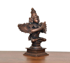 Copper Garun Bhagwan idol, three-quarter view, folded arms, wing feather details