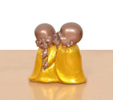 Resin laughing Buddha monk sculpture, close view of two monks hugging in yellow robes