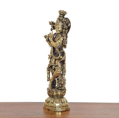 Brass Lord Krishna idol holding flute, angled view with intricate carved jewelry