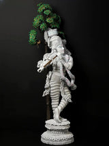 Standing Krishna idol statue with gold flute, white body, garlands, and green tree motif
