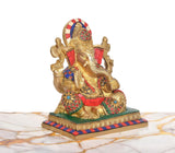 Ganesha brass idol at angle, multicolor accents on crown, arms, and robe