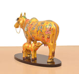Side view resin Kamdhenu cow with calf, colorful traditional artwork on body.