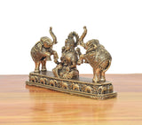 Angled view of seated Lakshmi statue with two elephants; engraved base with patterns.