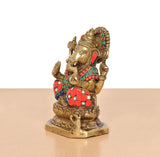 Brass Ganesha statue in side profile, jeweled crown, red-and-green patterned attire