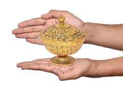 Gold metal dry fruit bowl showpiece held in hands, detailed decorative lid