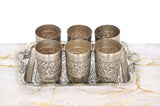 Six silver-toned engraved cups on a decorative tray, centered arrangement