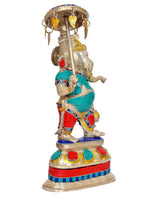 Brass Ganesha figurine holding umbrella, standing on tiered base; teal and red