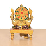Back view of brass Ganesha statue with decorated round halo and meenakari base