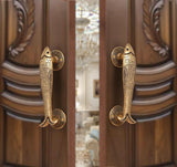 Brass fish design door handle pair with round backplates, shown on a door.