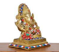 Brass Ganesha idol angled view; painted jewels on crown and red-blue ornaments
