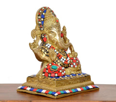 Brass Ganesha idol angled view; painted jewels on crown and red-blue ornaments