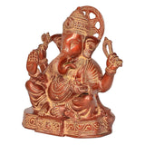 Brass Ganesh statue side view, seated pose with four arms and engraved face
