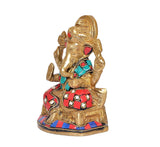 Side view brass Ganesha idol holding ornaments, red and turquoise jeweled attire