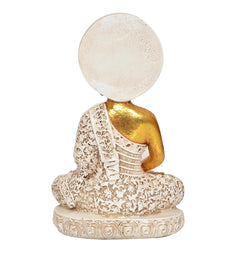 Back view of seated Buddha statue, gold shoulders, white textured robe, round halo