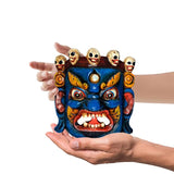 Hand-held deity wall mask with blue face, red fangs, and small skull figures on top