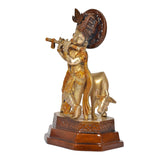 Brass Krishna figurine playing flute, side view on cow, textured halo disk