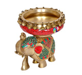 Brass elephant figurine with red urli bowl, colorful peacock-style ornament