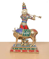 Back view of Krishna on cow idol, brass figure with colorful patterned clothing
