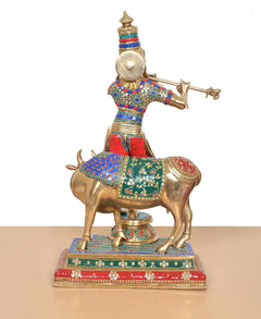Back view of Krishna on cow idol, brass figure with colorful patterned clothing