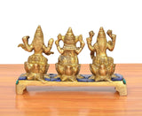Back view of golden brass Lakshmi, Ganesha & Saraswati idols on multicolor platform