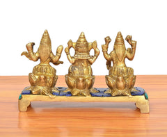 Back view of golden brass Lakshmi, Ganesha & Saraswati idols on multicolor platform