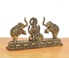 Brass Lakshmi seated statue, elephants on either side, engraved base details visible