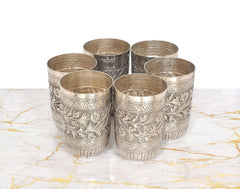 Close view of six silver-toned engraved glasses on the decorative tray