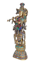 Brass Krishna murti holding flute, gold-toned figure with multicolor patterned attire