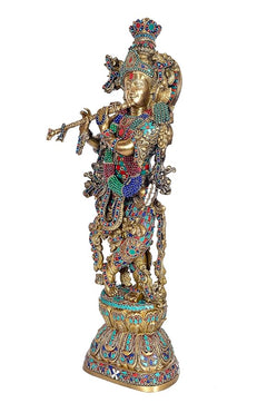 Brass Krishna murti holding flute, gold-toned figure with multicolor patterned attire