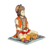 Hanuman-Idol in Harz, seitlich: detaillierte Ornamente, orange Tuch, Hände ruhen am Schoß
