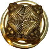 Brass emblem close-up: engraved rosette wheel pattern on round plate
