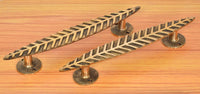 Golden brass leaf door handle pair laid out, with leaf bars and round bases