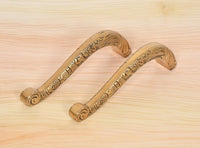 Ornate brass door pull handle pair with curved grips and golden finish.