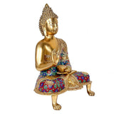 Brass Buddha idol side view, seated with hand near bowl, patterned blue-red robe