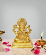 Brass Ganesha idol with four arms and ornate crown, on a pedestal base