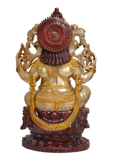 Back view of seated Ganesha idol with dark red halo and gold-tone ornaments