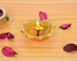 Metal oil diya lamp, gold lotus-shaped holder with lit flame in center