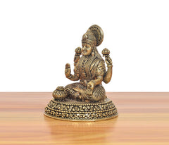 Lakshmi-Idol in Messing, seitliche Ansicht: sitzende Figur mit erhobenen Armen und Schmuck