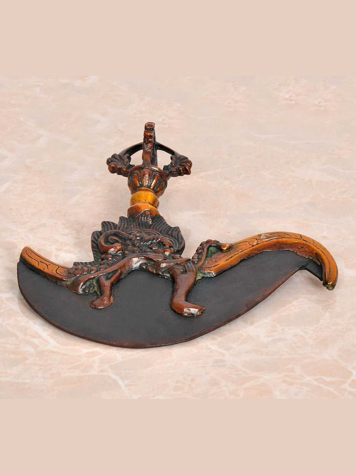 Brass dorje flaying knife top with dark crescent blade and ornate handle, front view