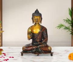 Brass Buddha statue seated in Abhaya mudra, gold face and dark robe, 9-inch